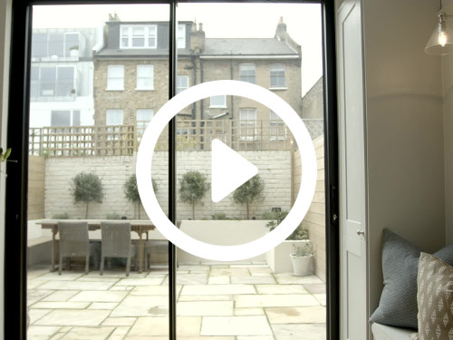 Home kitchen interior featuring glass sliding doors with sub-urban views to rear garden area and neighbouring brick houses  Zoom background