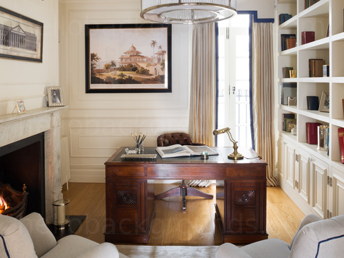 Homey private office featuring classic wooden desk and office chair next to marble fireplace  Skype background