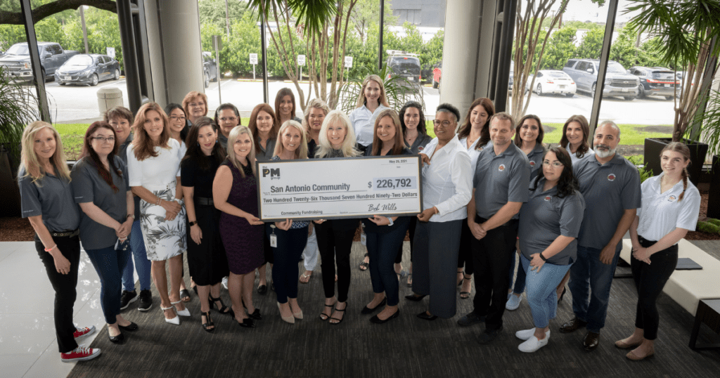 An image of PM Group staff as well as the staff of five nonprofits holding a check of total donations of 226,792 dollars