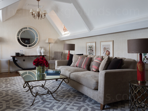 Loft style living room featuring prominent circular interior window with large grey sofa and glass coffee table  Google Meet background