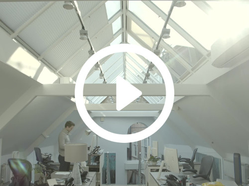 Contemporary triangular loft style office workspace with windowed glass ceiling allowing natural light Google Meet background