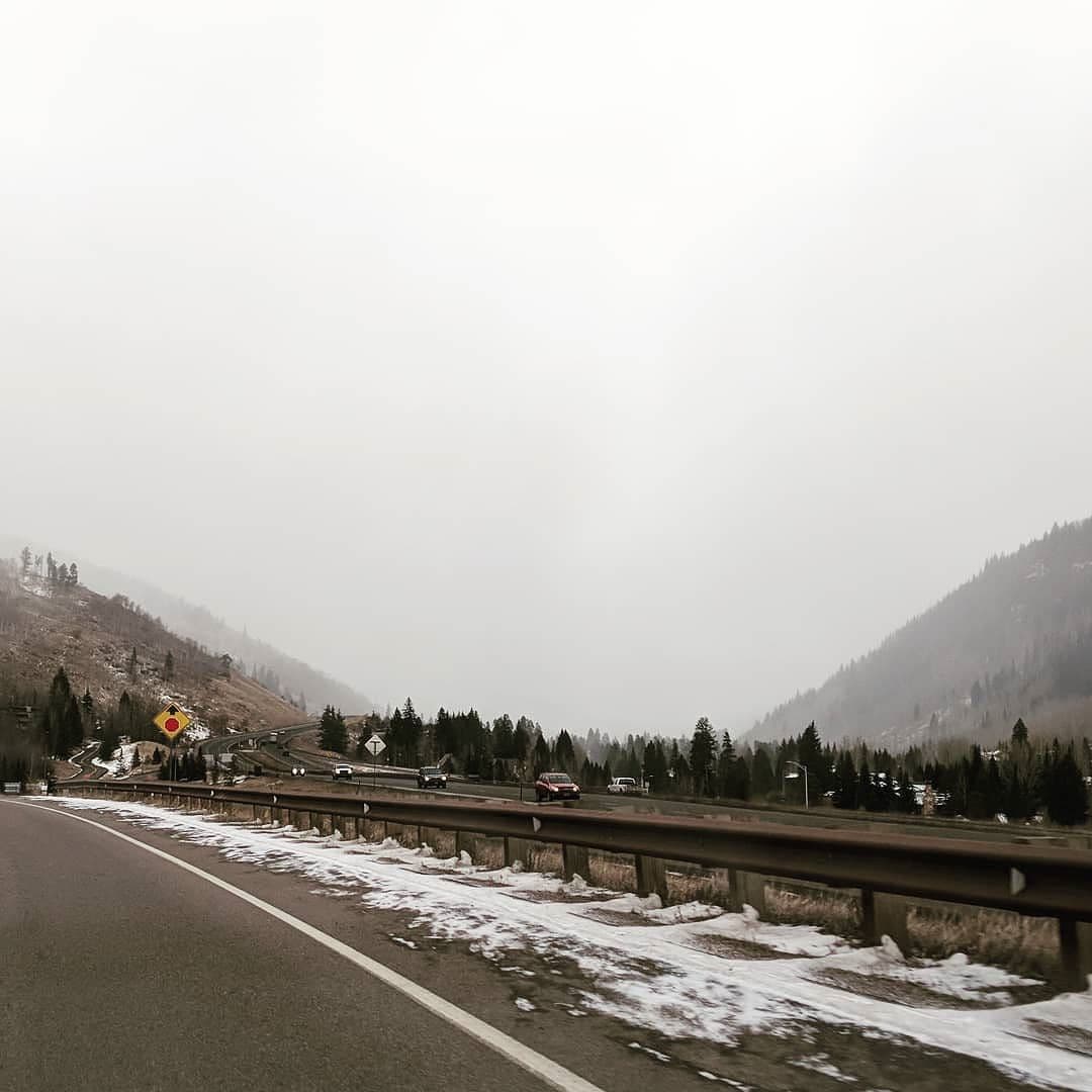 A mountain highway. A winter snowstorm completely obscurs the valley the road emerges from.
