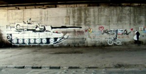 Ganzeer’s tank versus bike (with Sad Panda in melancholy pursuit), under the October 6th Bridge. Copyright suzeeinthecity.wordpress.com.