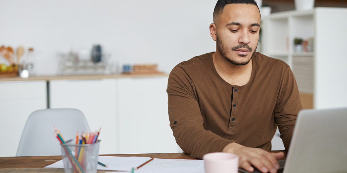 Design Degree vs. UX Bootcamp: Which Is Best? An aspiring UX designer at a desk, researching UX design degrees and bootcamps