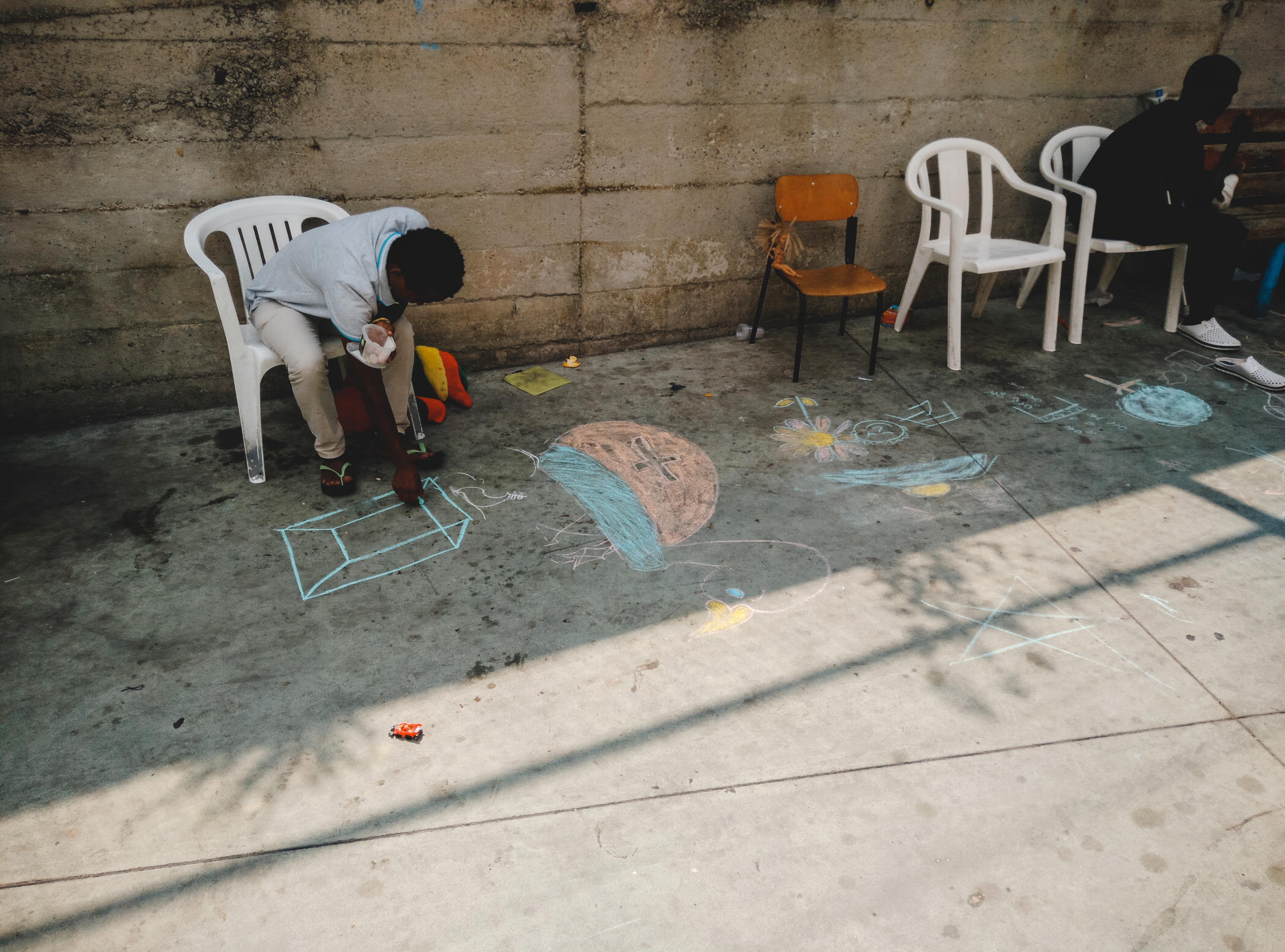 un migrante disegna a terra con un gesso un migrante disegna a terra con un gesso