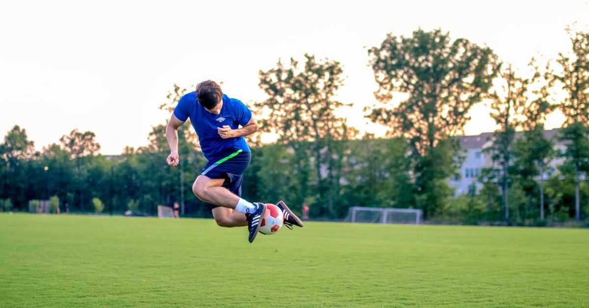 Ein Fußballspieler springt in die Luft, während er einen Trick mit dem Fußball vorführt