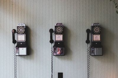 Three old-fashioned phones hanging on a wall.