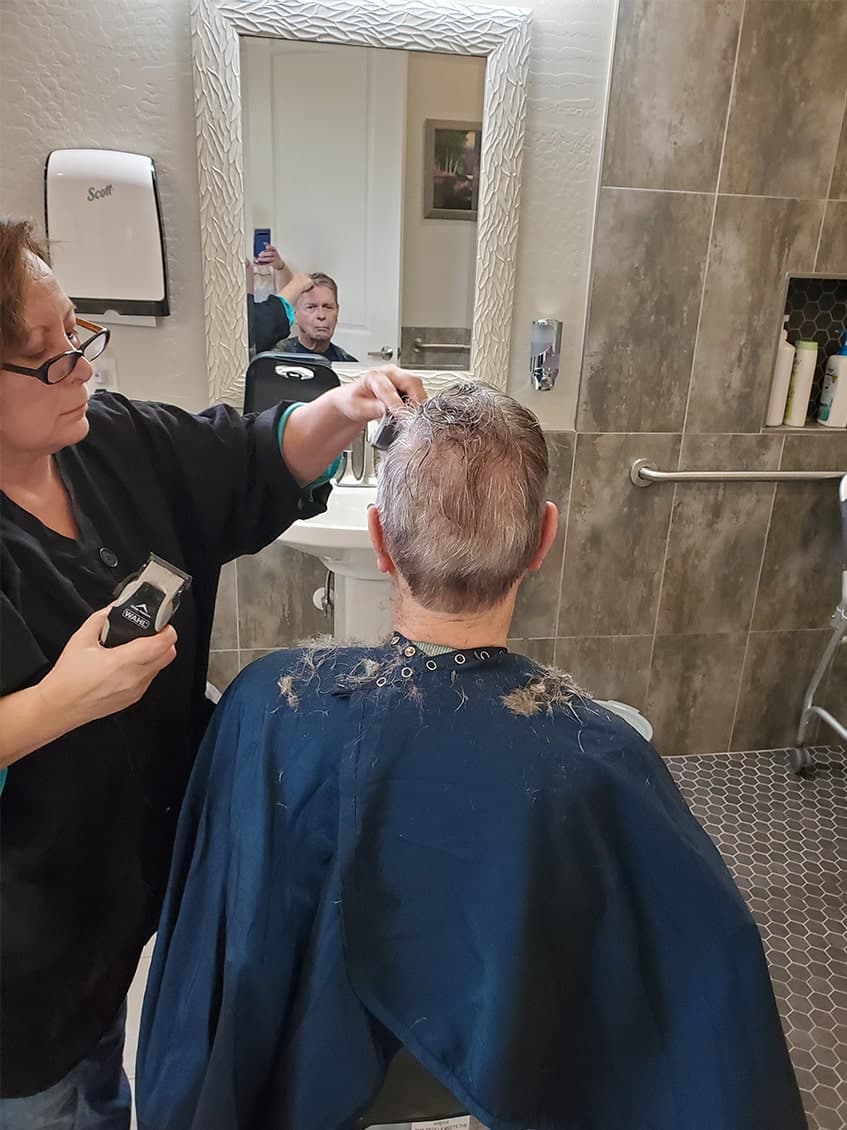 Caretaker providing haircut to patient