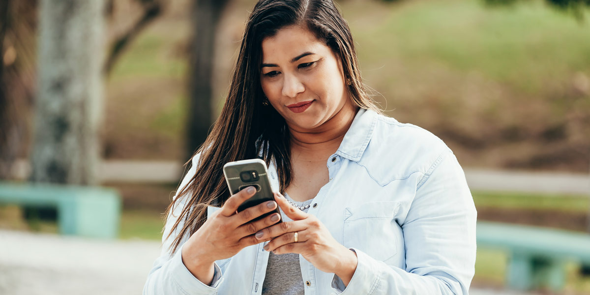 What Are Affordances in UX Design? A user standing in a park, working on her phone.