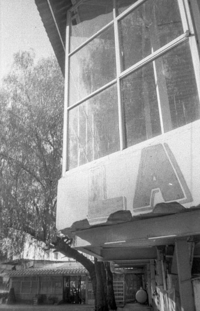 A sign that says “LA” painted below a window of a small and dusty shop
