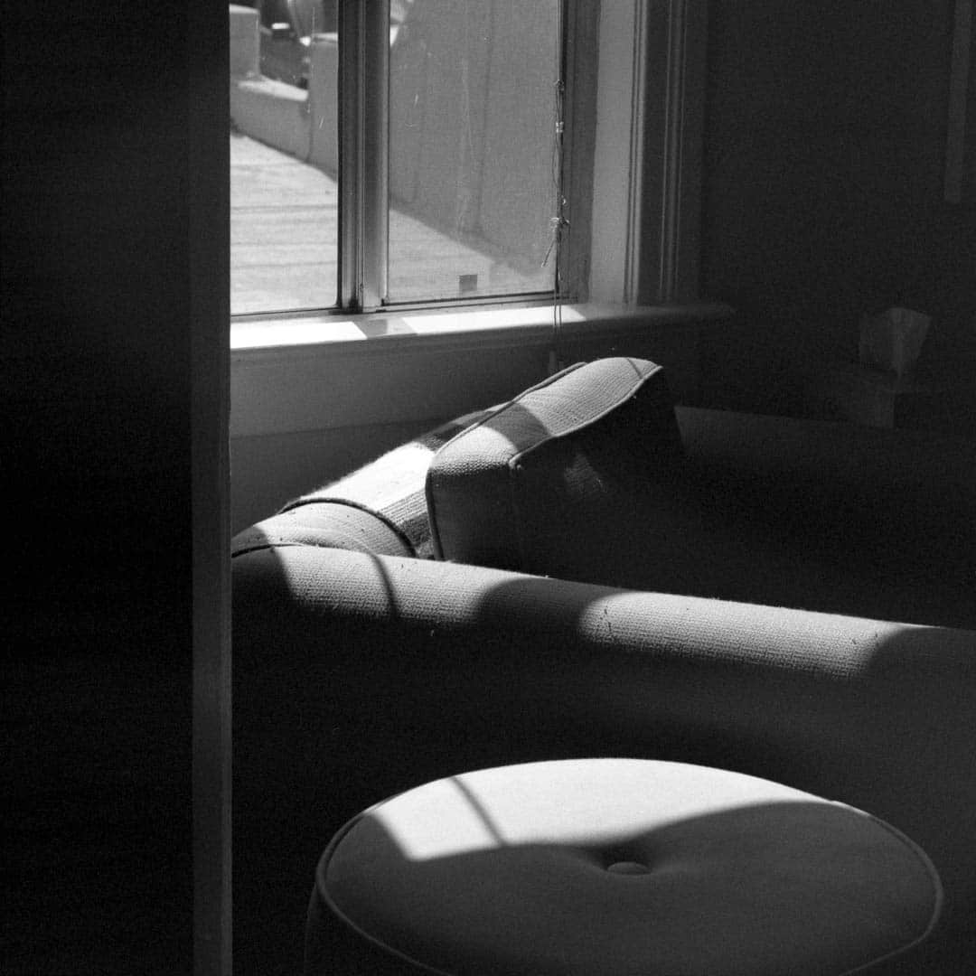 Sunlight flooding through a window onto a stuffed chair and ottoman