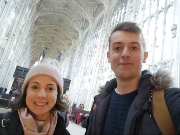 Myself and Naomi, smiling in the foreground, with the inside of a cathederal in Cambridge in the background.
