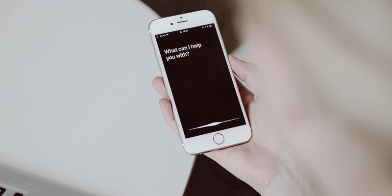 A user interacting with their smartphone using voice technology, a key UX trend A user holding their smartphone, issuing a voice command