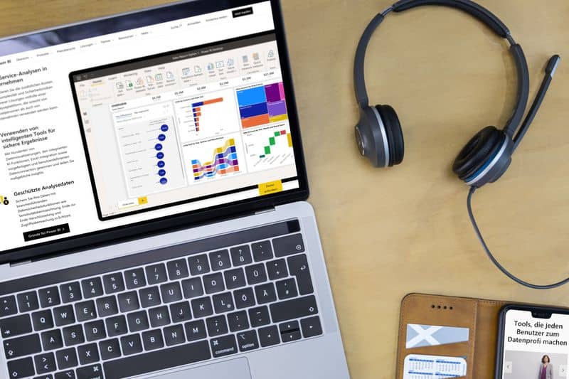 Self-Service Intelligence mit Power BI Foto von einem Laptop mit Power BI-Bericht, Handy und Headset