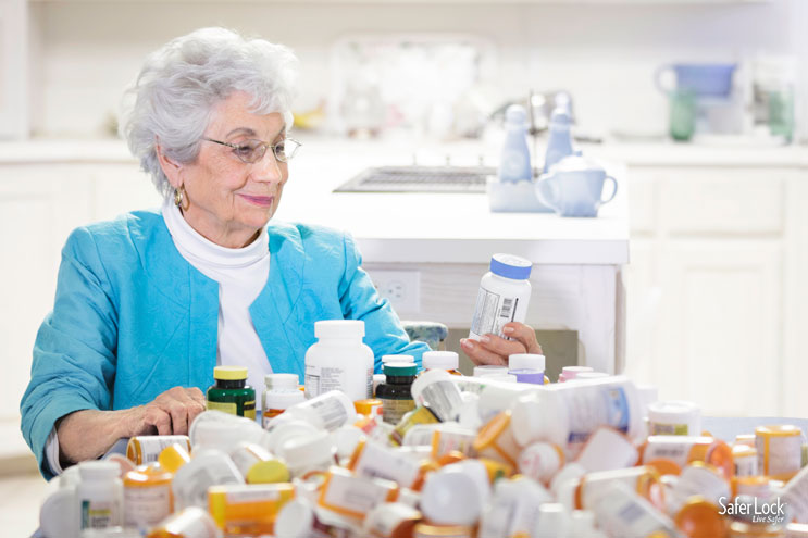 A senior woman sitting at her kitchen table surrounded by prescription bottles.