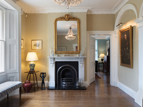 Classic style wooden floored hallway featuring prominent ornate fireplace with overhanging decorative mirror Skype background