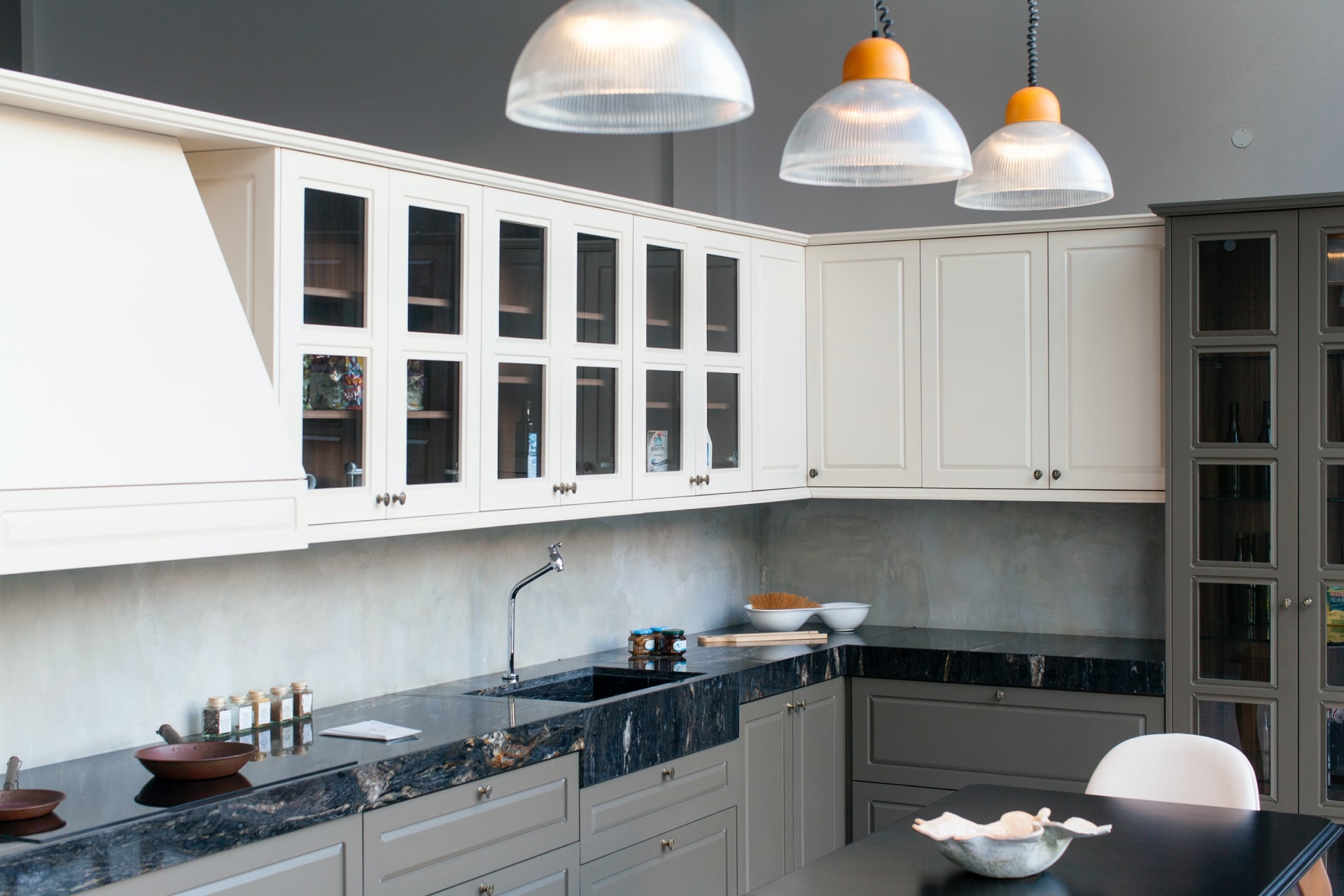 Imagen de una cocina moderna y espaciosa. Combina armarios superiores blancos con gabinetes grises y una encimera de mármol negra