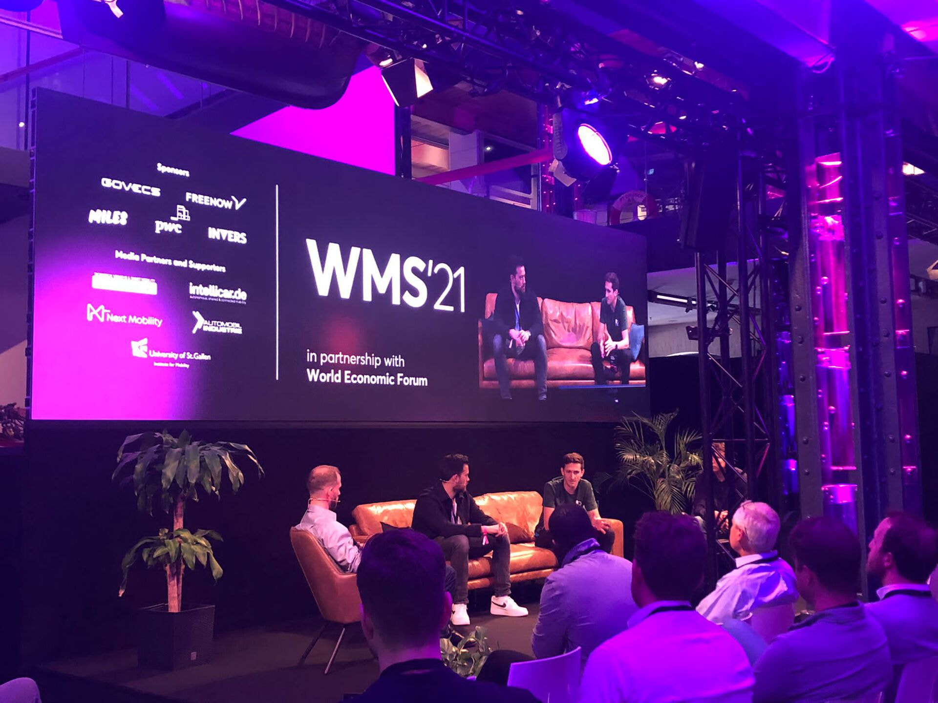 Three caucasian males sitting on stage of the WMS21 in front of an audience.