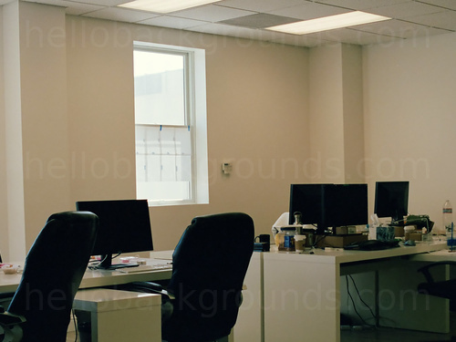 Simple workspace with tiled ceiling above white computer desks and black office chairs Zoom background