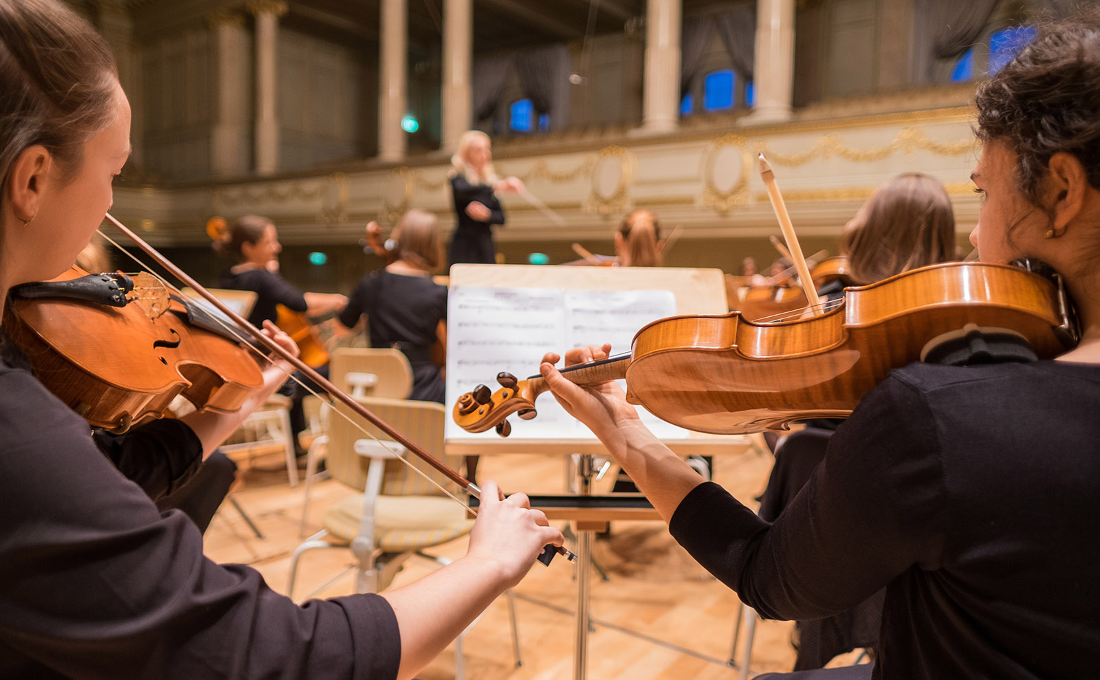 young people playing the violin in an orchestra