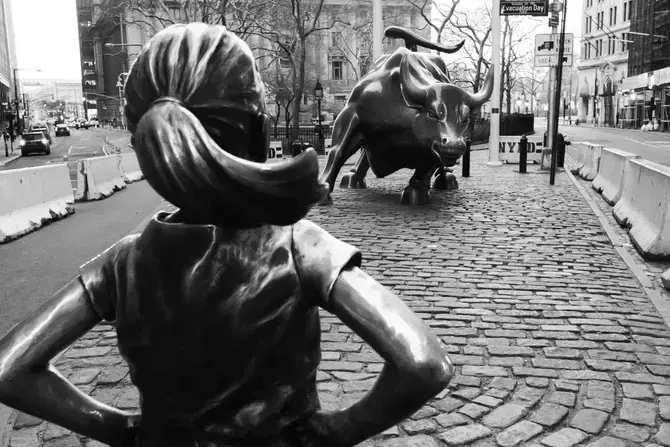 a statue of a bull facing a girl, from behind the girl