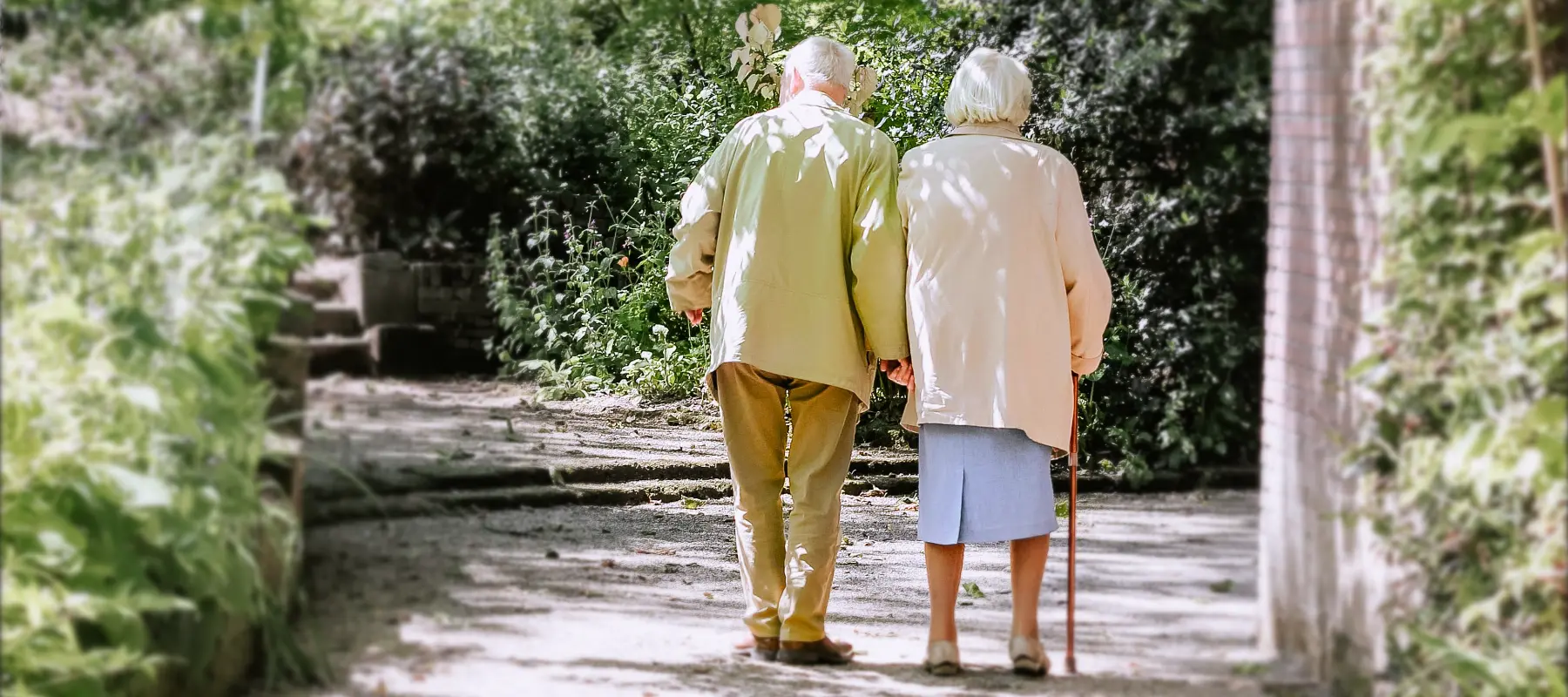 Um casal de idosos caminhando de mÃ£os dadas em um jardim