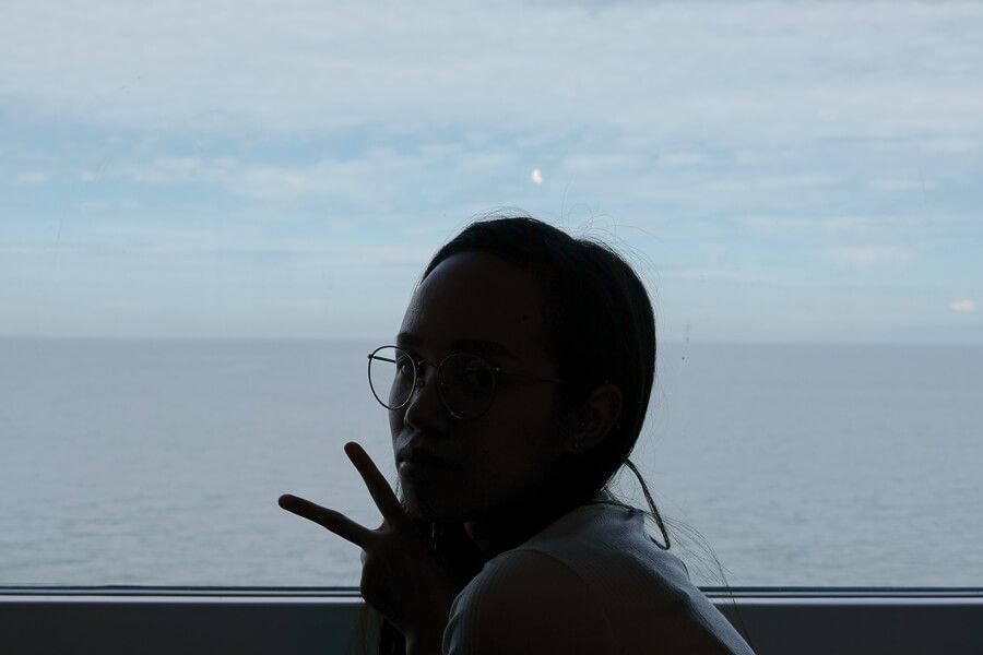 Me posing in front of a window, throwing a peace sign.
