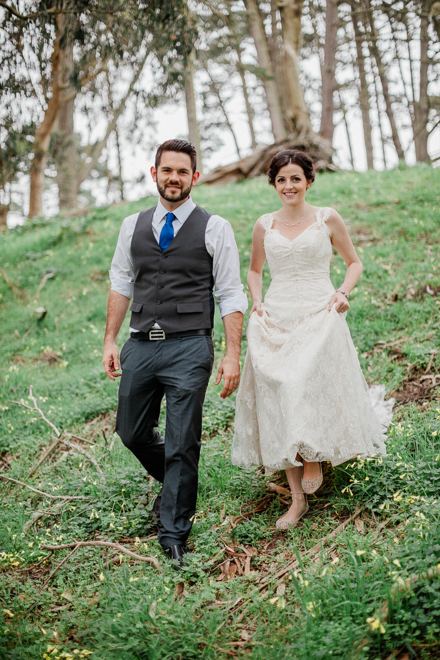 portrait of a bride and groom walking on grass