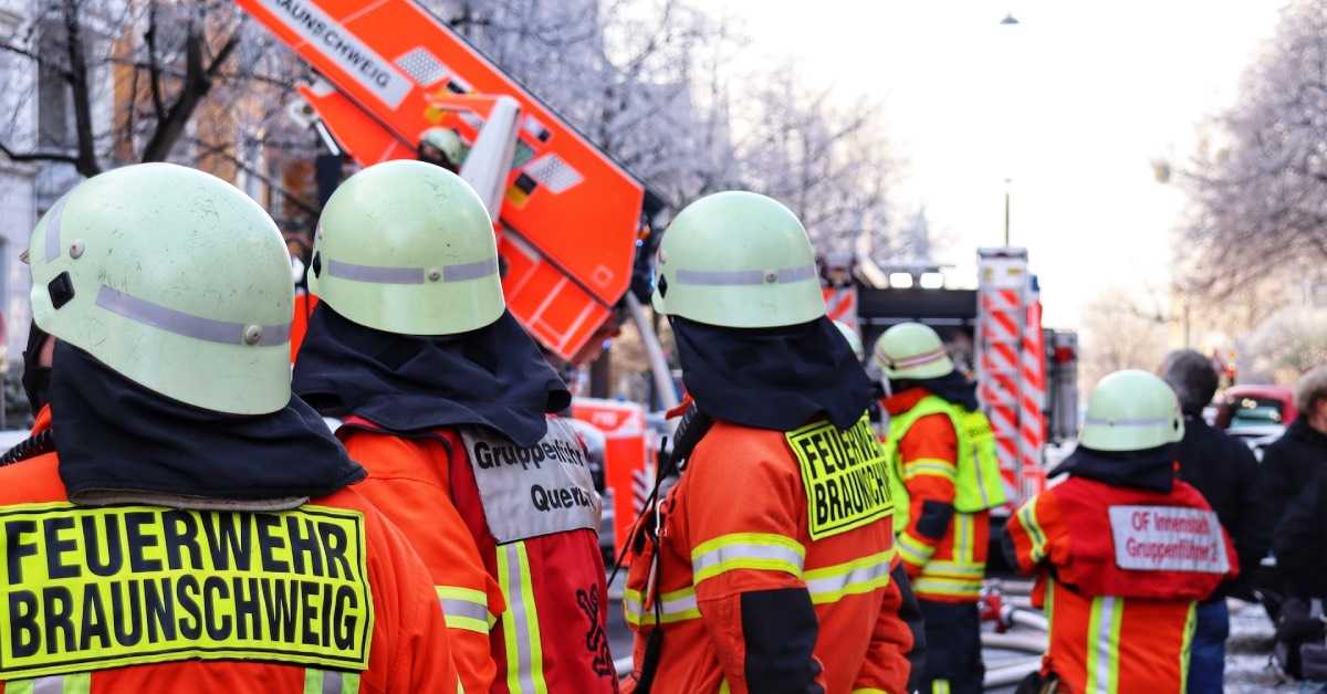 Mehrere Mitglieder einer Feuerwehr Gruppe bei einem Einsatz, bei zweien ist auf der Uniform auf dem Rücken der Schriftzug "Gruppenführer" zu lesen.