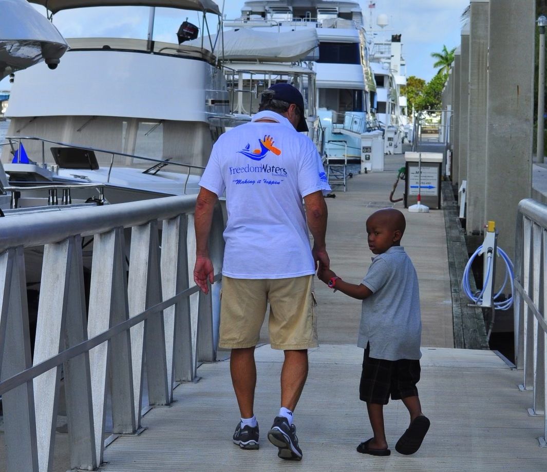 Andrew Cilla holding the hand of a boy participating in Freedom Waters Outing