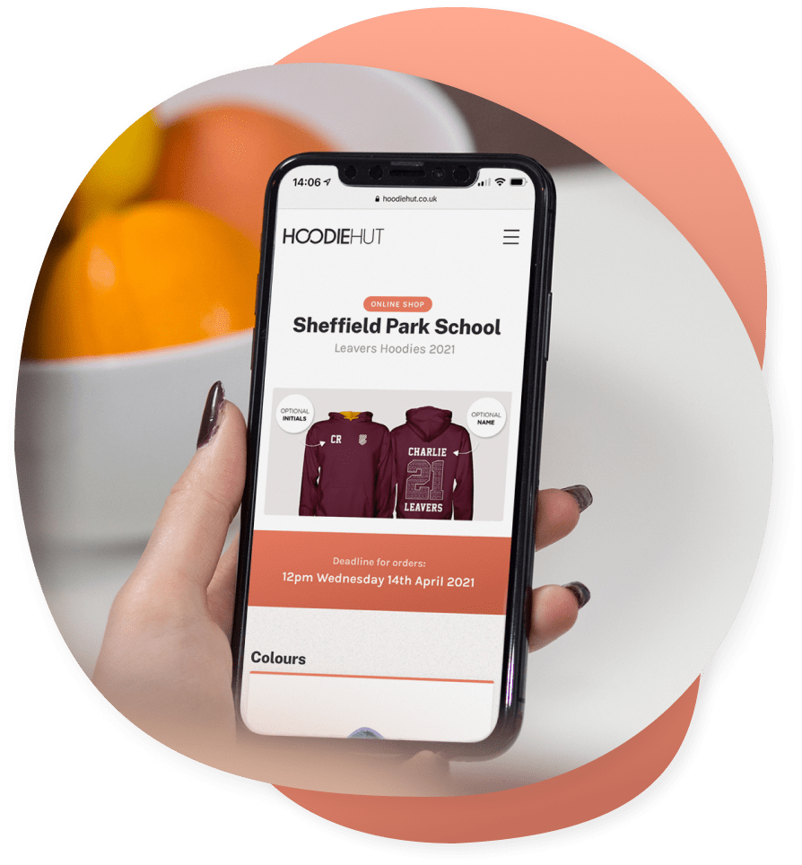 A student holding an iPhone that shows the leavers hoodies online shop page