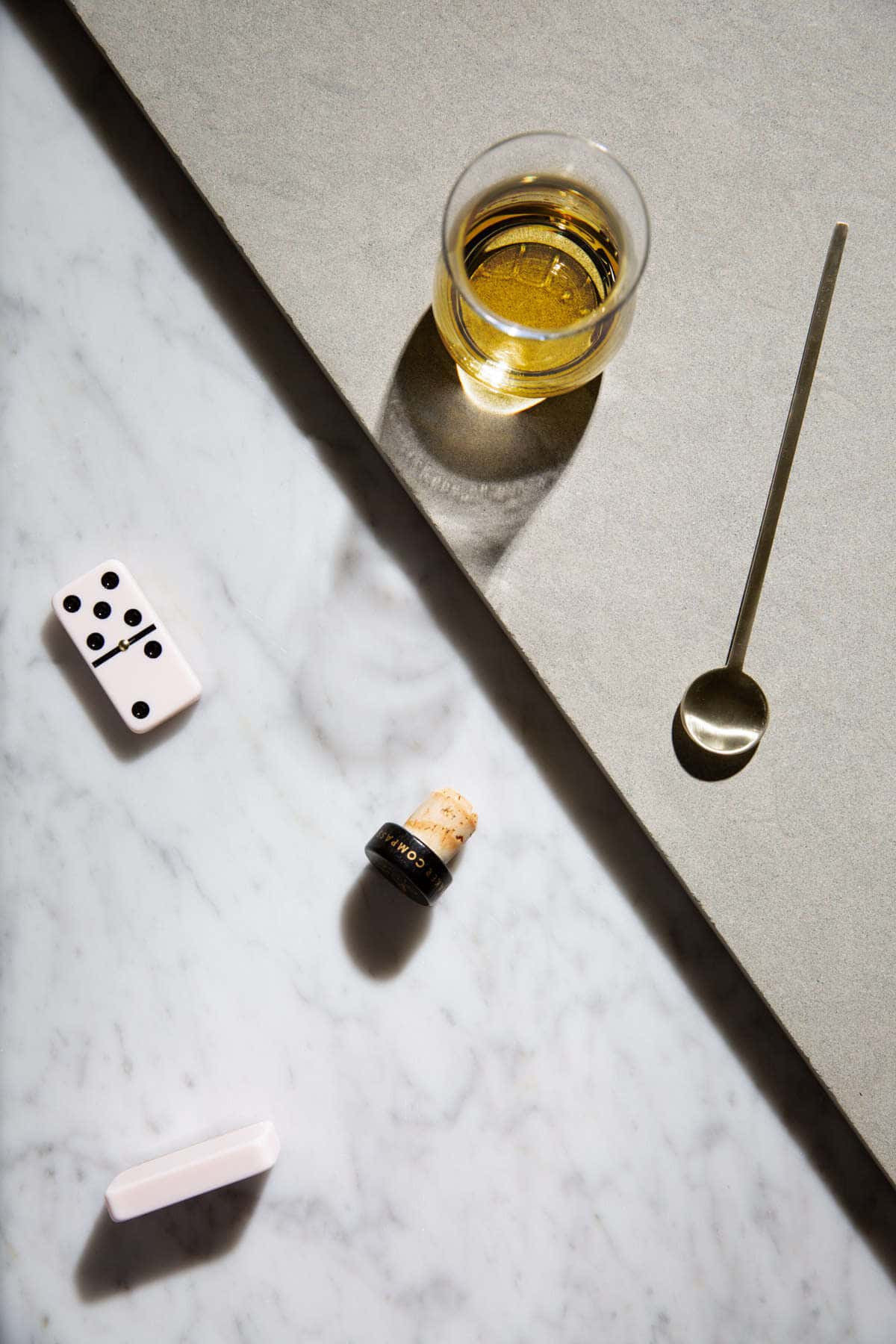 whiskey with dominos next to the glass on marble top