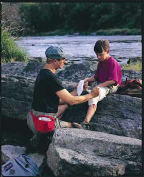Man administering minor first aid to child on a rock