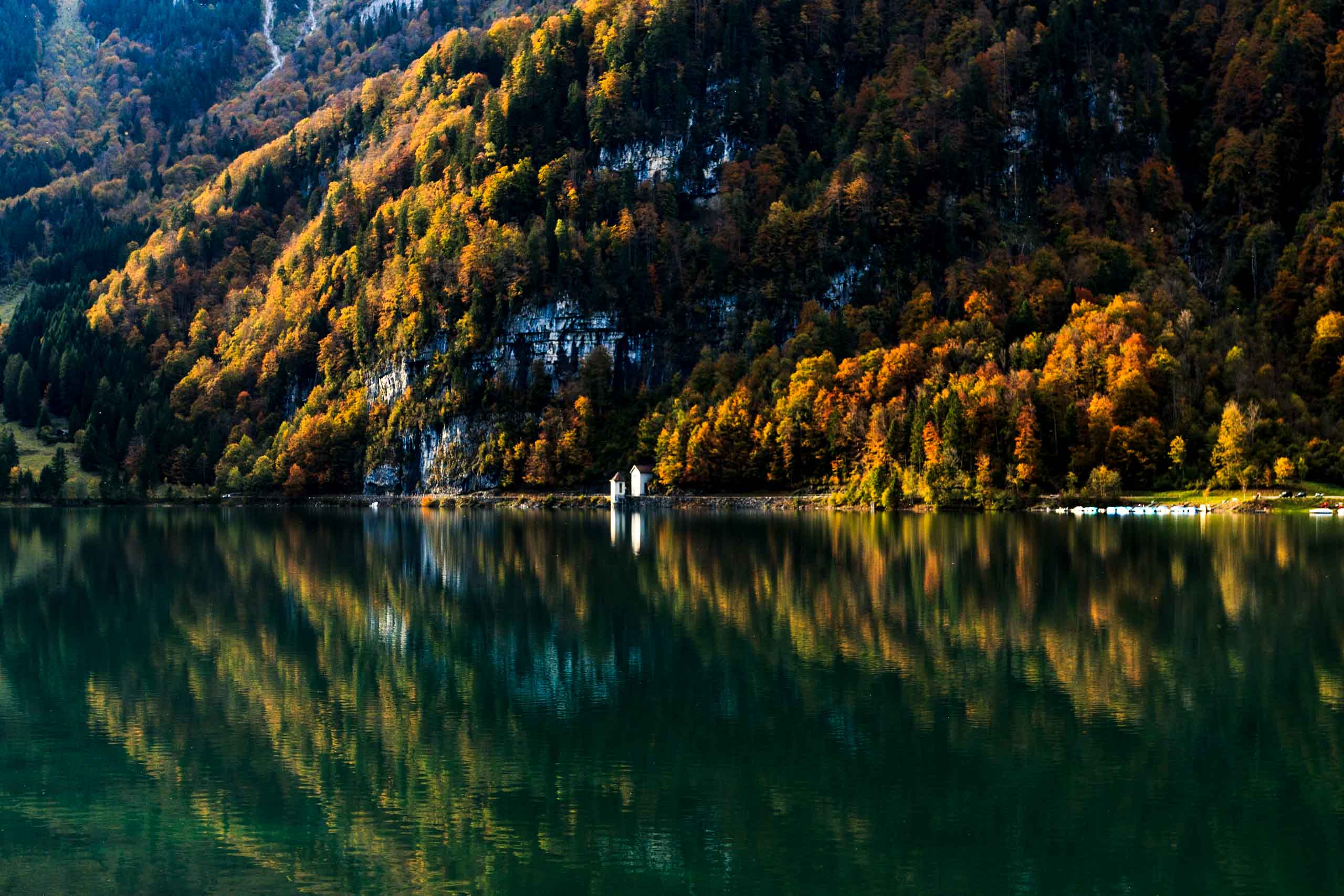 Building with autumn forest in the background. Reflection in lake.
