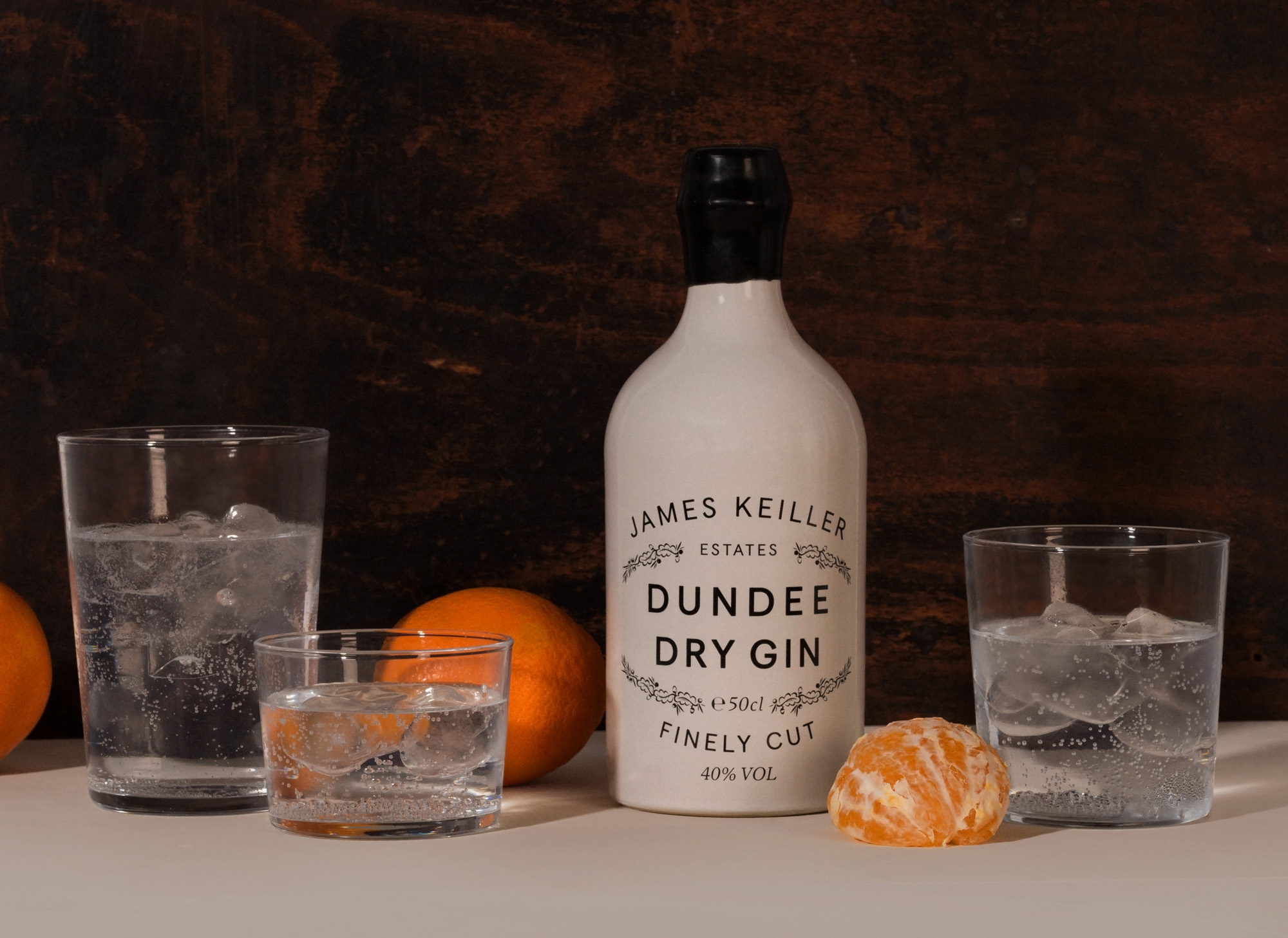 Keillers Dundee Dry Gin with oranges and glasses of liquid and ice