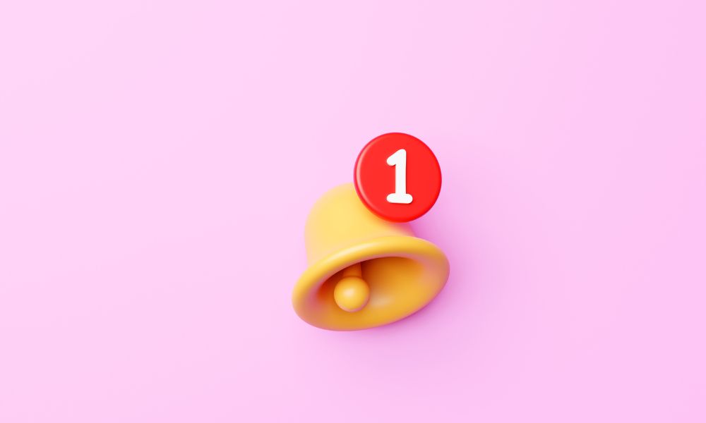 On a pink background is a bell icon. The bell has the number 1 on top of it emphasizing a notification, commonly seen on websites and mobile apps.
