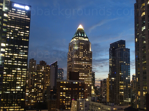 Urban cityscape at night featuring multiple tall office buildings with prominent pyramid topped building in centre Skype background