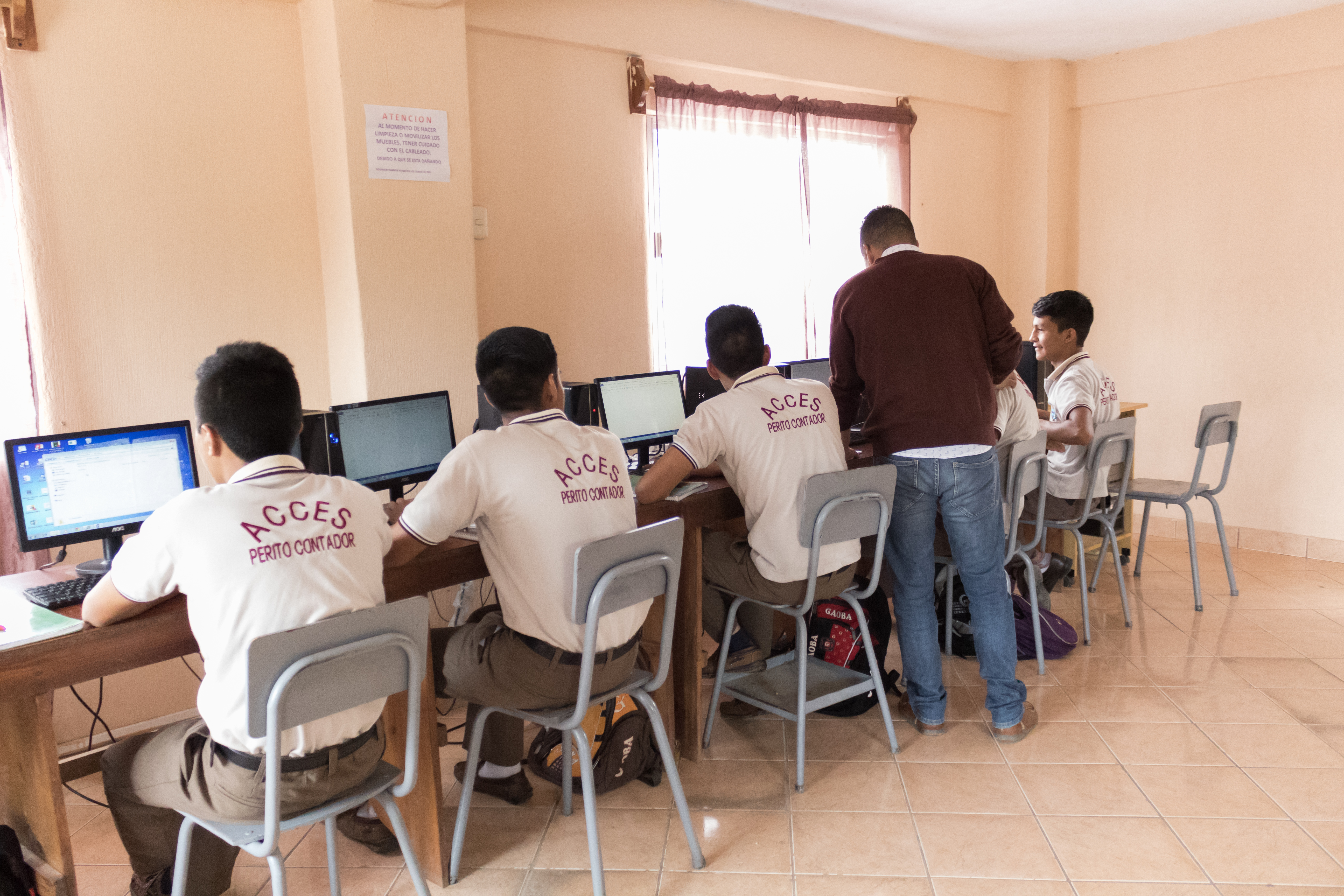 male students facing computer with teacher