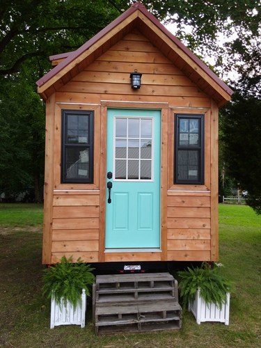 Front view of the login cabin tiny house, showing the front door, front light and windows. Front view of the login cabin tiny house, showing the front door, front light and windows.