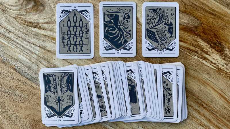 A deck of divination cards, about the size of a regular playing card and featuring custom artwork in an angular, abstract style.