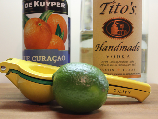 The ingredients to make a Blue Kamikaze mixed drink, including vodka, blue curacao and lime juice