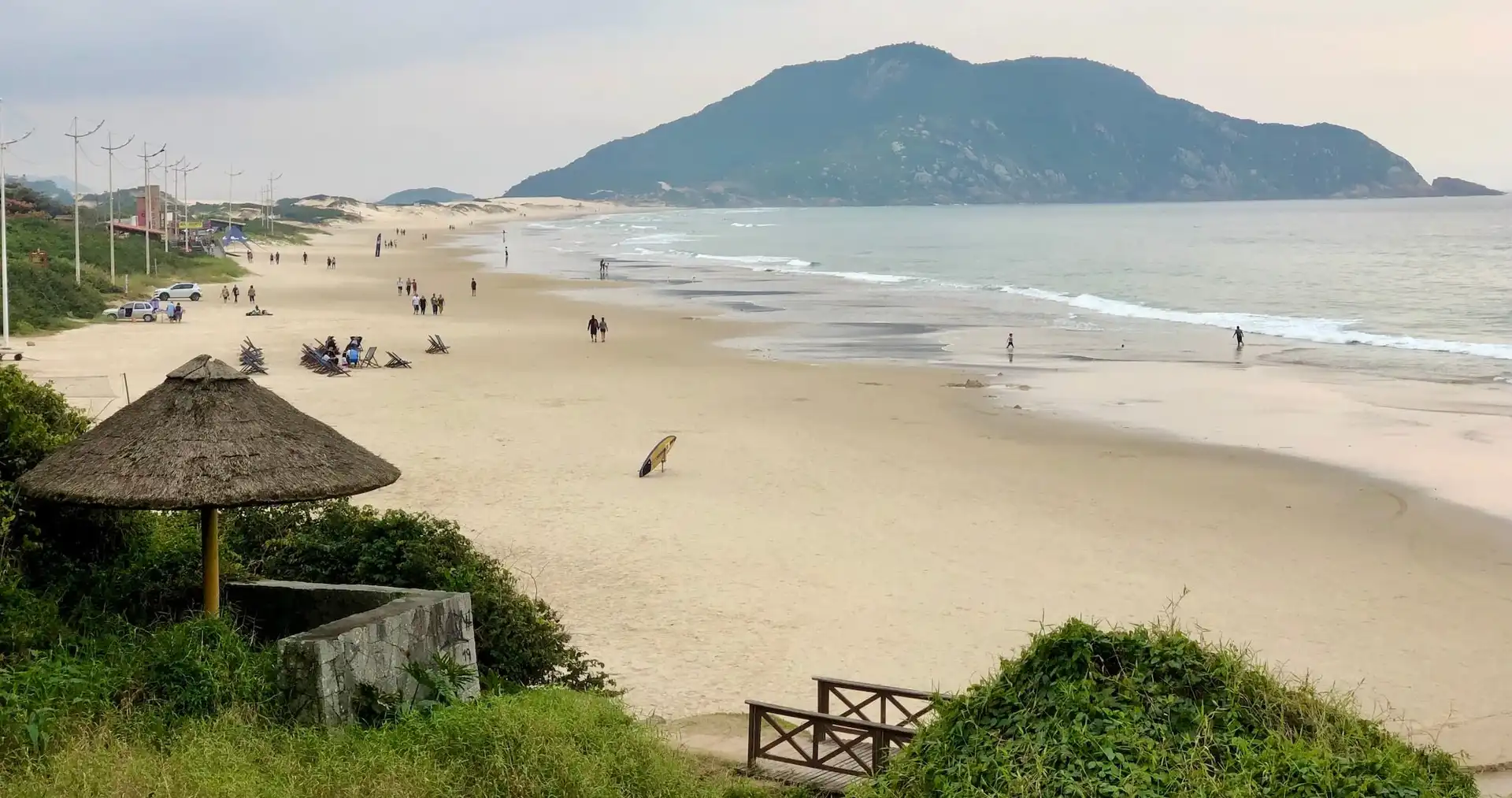 Vista da faixa de area da praia do Santinho, com mar a direita e montanha ao fundo