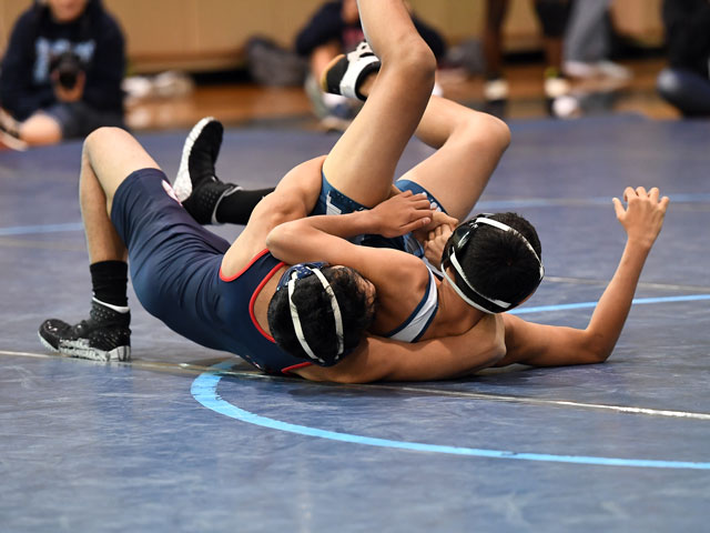 Two wrestlers grappling on the competition mat