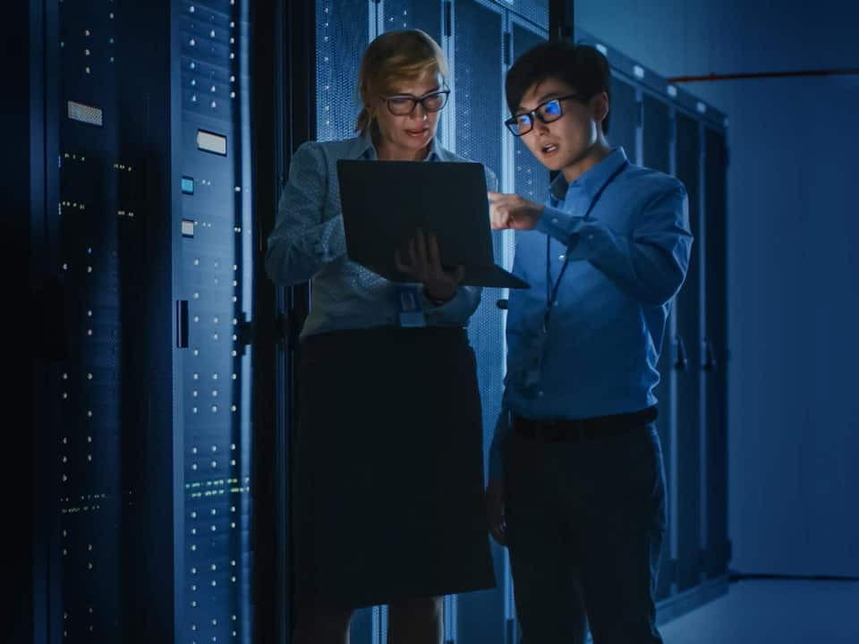 employees on a laptop next to a wall of servers