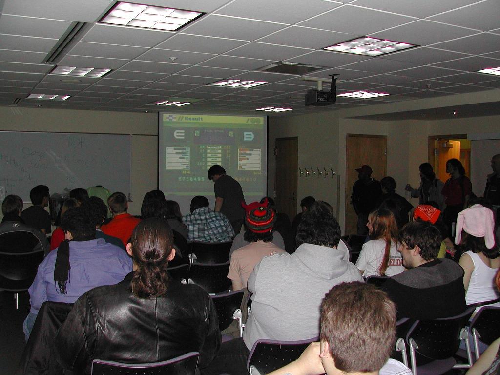 A dancing video game competition at Animarathon III. Many onlookers crowd arround.