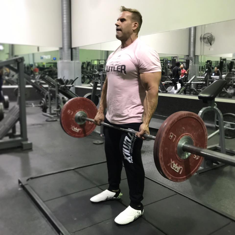 muscular man lifting barbell in gym
