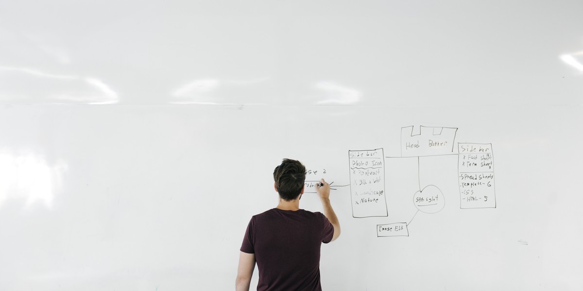 Ready to start learning about information architecture? A man working on information architecture against a large whiteboard