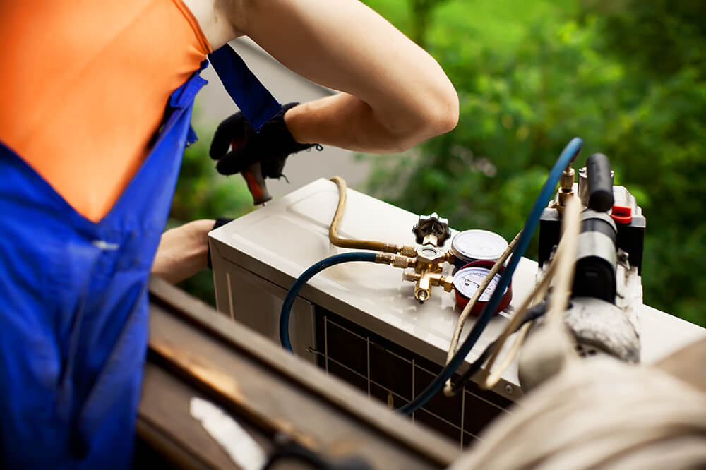 Photo of an HVAC repairperson fixing an AC unit