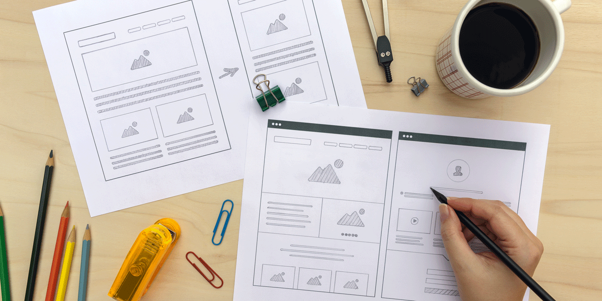 A designer creating a wireframe using pen and paper The hand of a designer drawing a wireframe using pen and paper on a table