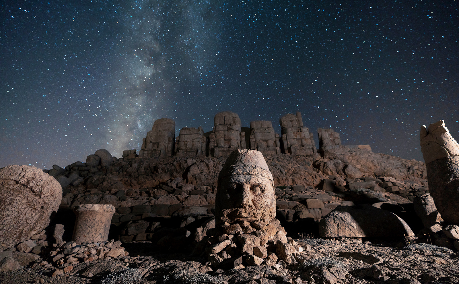 ancient carved stone heads under a starry sky on a mountain top